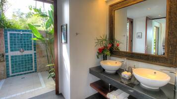 A bathroom with two sinks, a large mirror, and a shower area with a tiled wall.