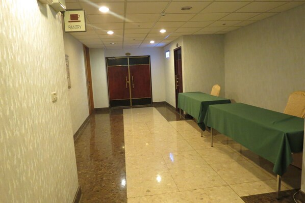A hallway with a sign for the pantry, a double door, and a table with a green tablecloth.