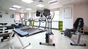 Un gimnasio con diversos equipos de ejercicio, incluyendo cintas de correr, bicicletas estáticas y máquinas de pesas.