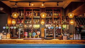 Un bar doté de nombreux robinets et d’étagères remplies de bouteilles d’alcool.