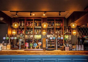Un bar con múltiples grifos y estantes llenos de botellas de licor.
