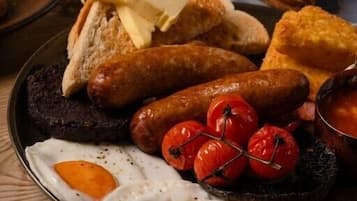 Un plato de desayuno con huevos, salchichas, tomates y pan.