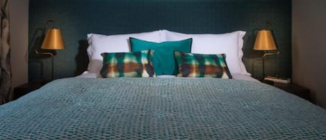 A neatly made bed with a patterned bedspread, two pillows, and two bedside lamps.