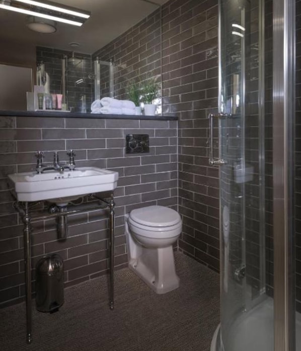 Un baño con un lavabo blanco, un inodoro y una ducha con mampara de vidrio.