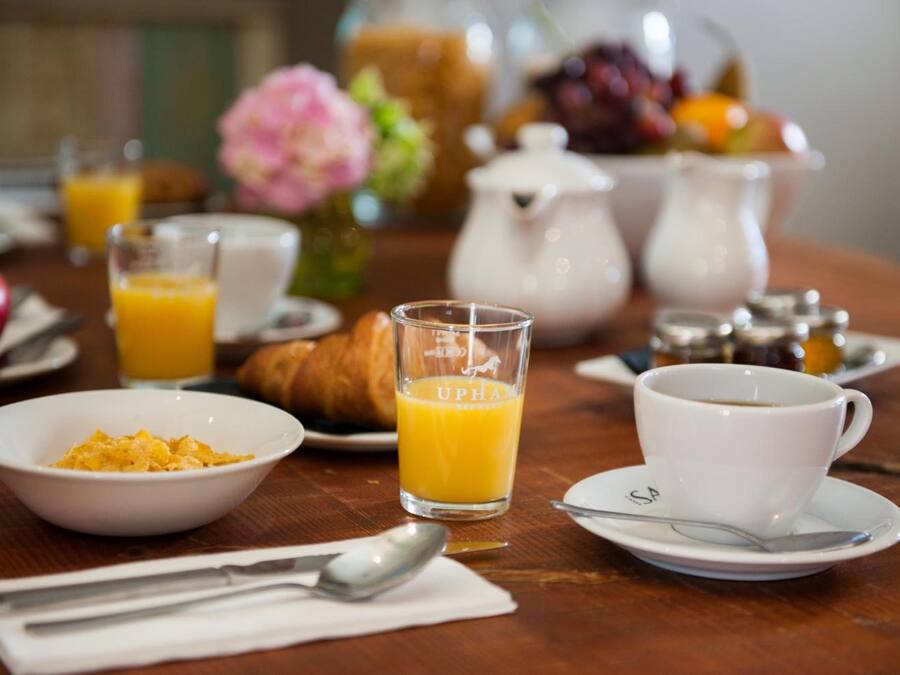 A breakfast setting with a croissant, orange juice, coffee, and a bowl of cereal.
