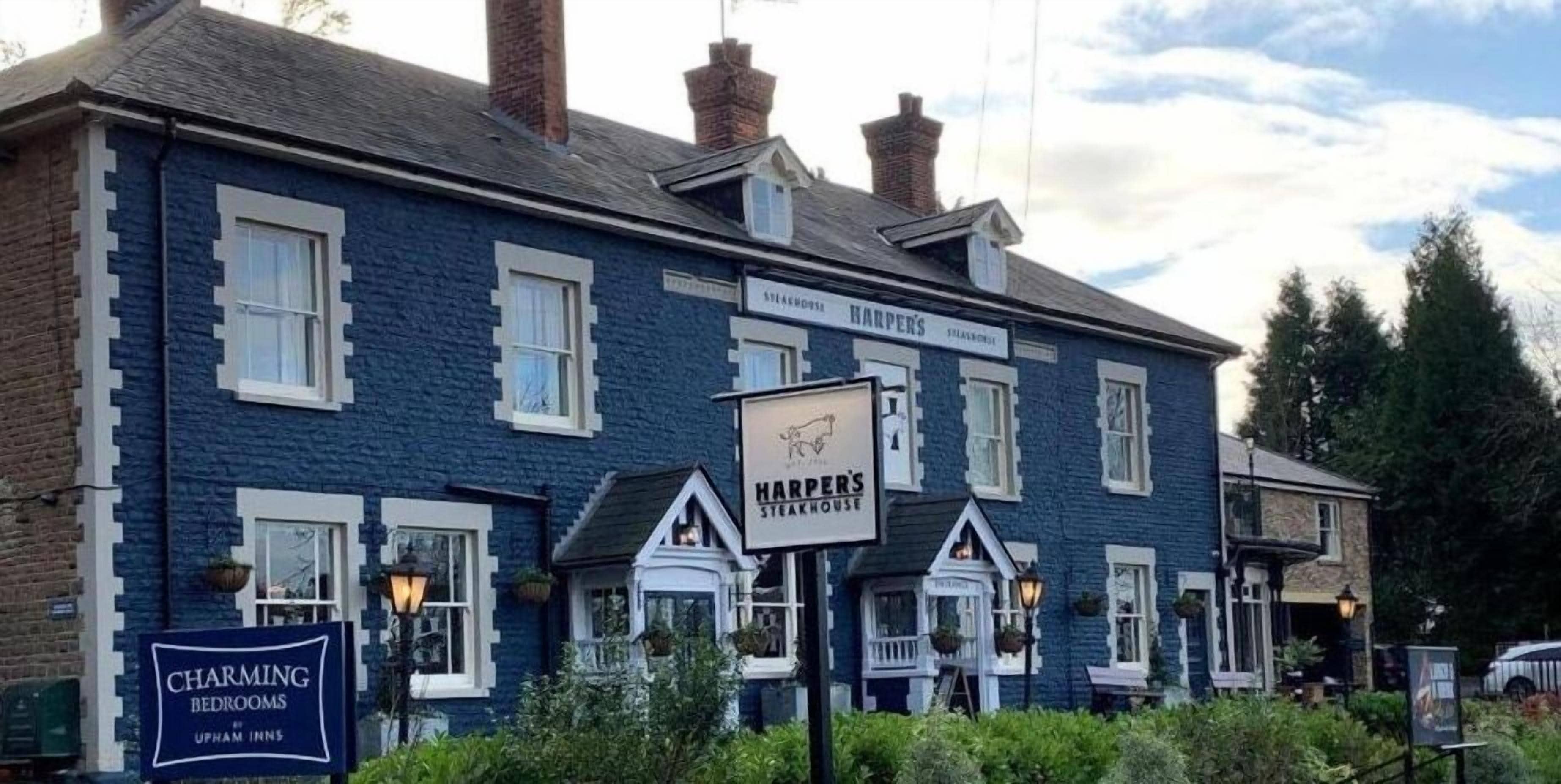 Un edificio tradicional con letreros que dicen 'Charming Bedrooms' y 'Harper's Steakhouse'.