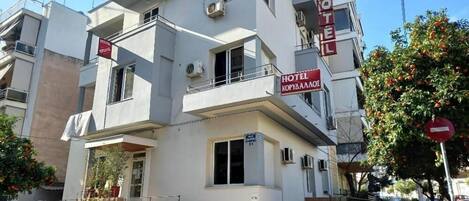 A multi-story hotel with balconies, air conditioning units, and a sign indicating it is a hotel.