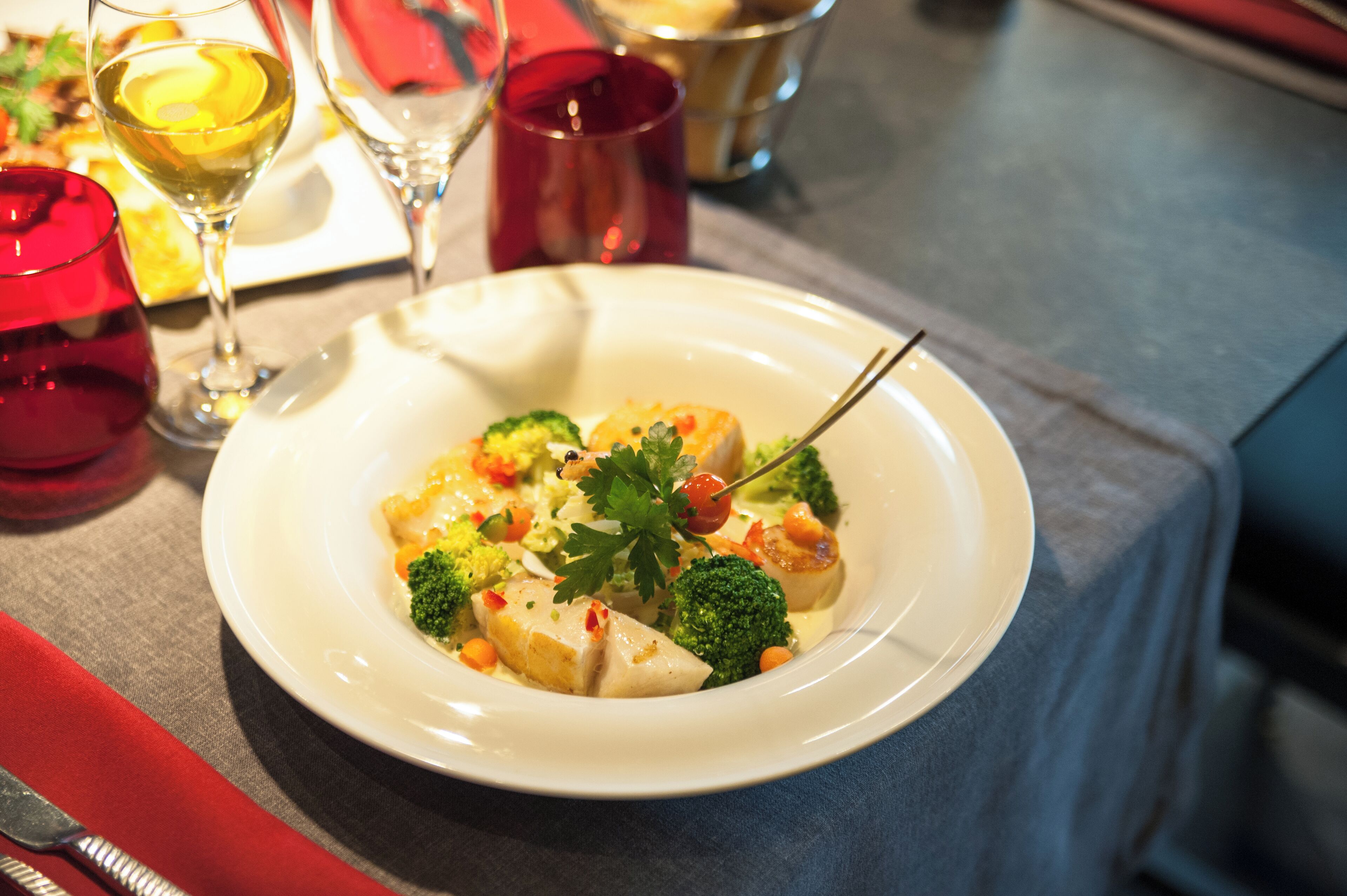 A plate of food with broccoli, carrots, and a garnish on a white plate.