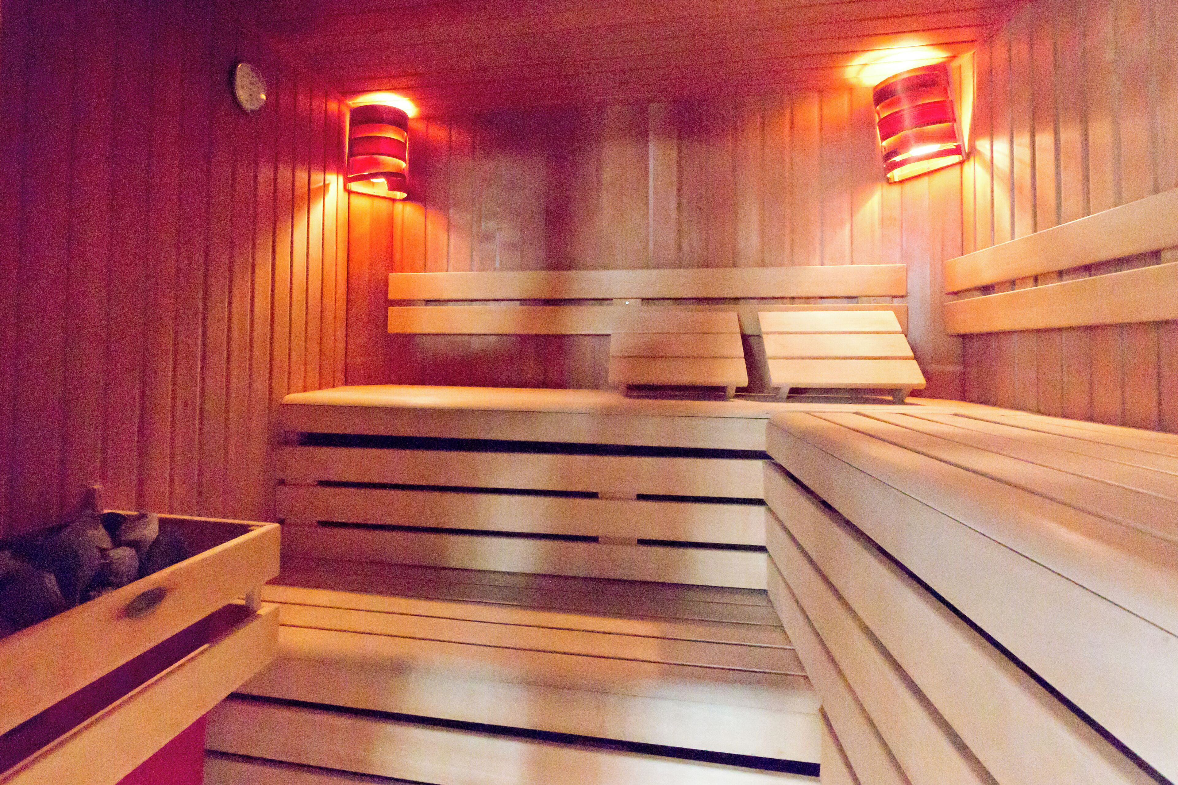 Una sauna con bancos de madera y asientos, un banco de madera con asiento, y un banco de madera con asiento.
