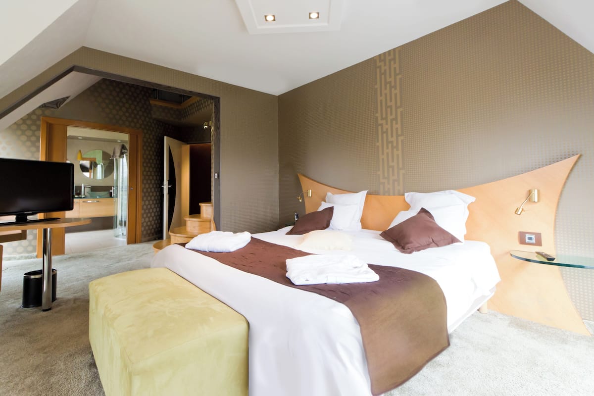 Een moderne hotelkamer met een groot bed, een televisie en een glazen salontafel.