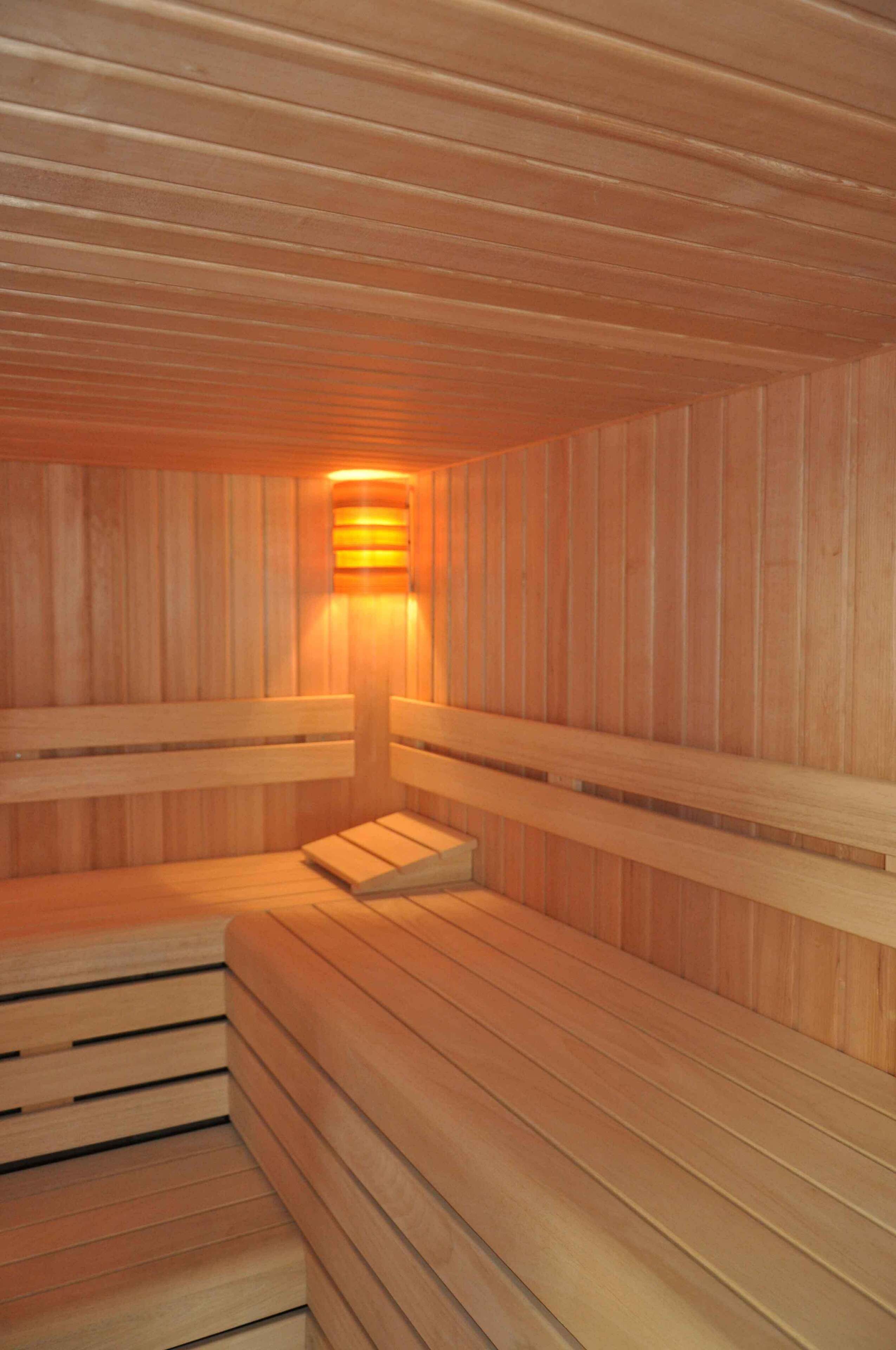 Una sauna con bancos de madera y una lámpara en el centro.