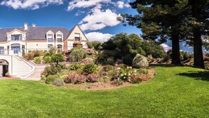 A large, two-story house with a prominent balcony and a landscaped garden.