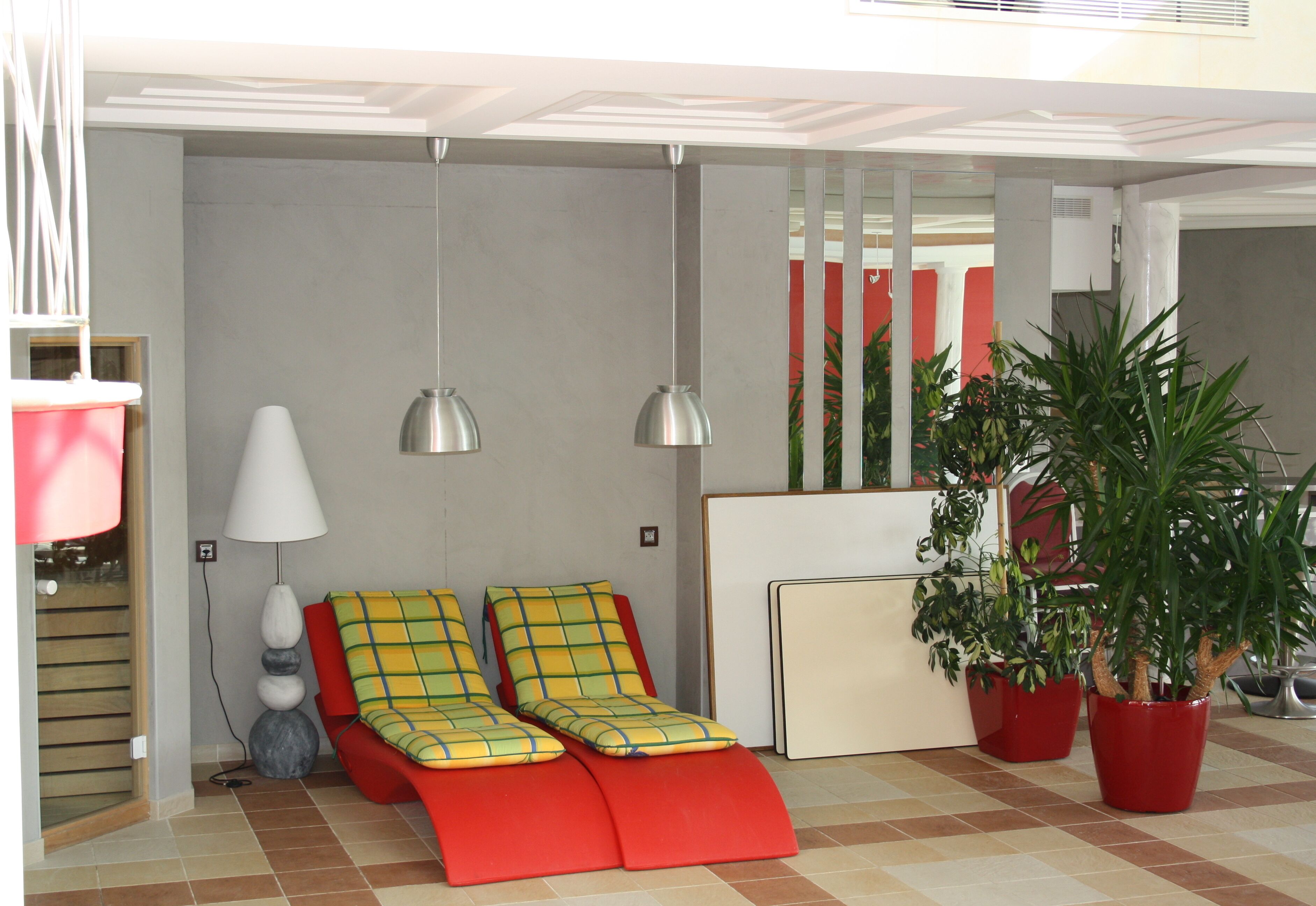 Une pièce avec un canapé rouge, une lampe et des plantes en pot.