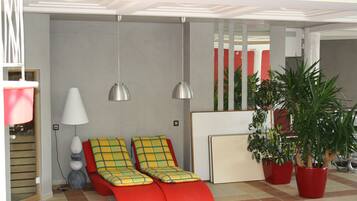 Une pièce avec un canapé rouge, une lampe et des plantes en pot.
