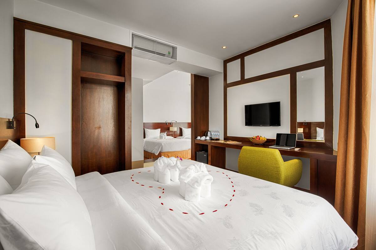 Une chambre d’hôtel avec un lit, un bureau avec un ordinateur, une télévision et une chaise.