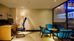 Una habitación de hotel con escritorio, computadora, lámpara y dos sillas azules.