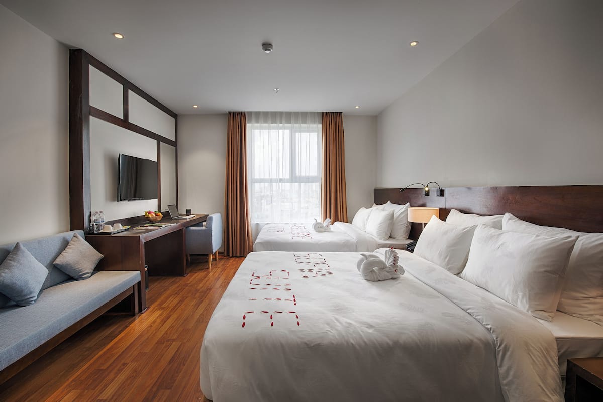 Une chambre d’hôtel avec deux lits, un canapé, un bureau et une télévision.