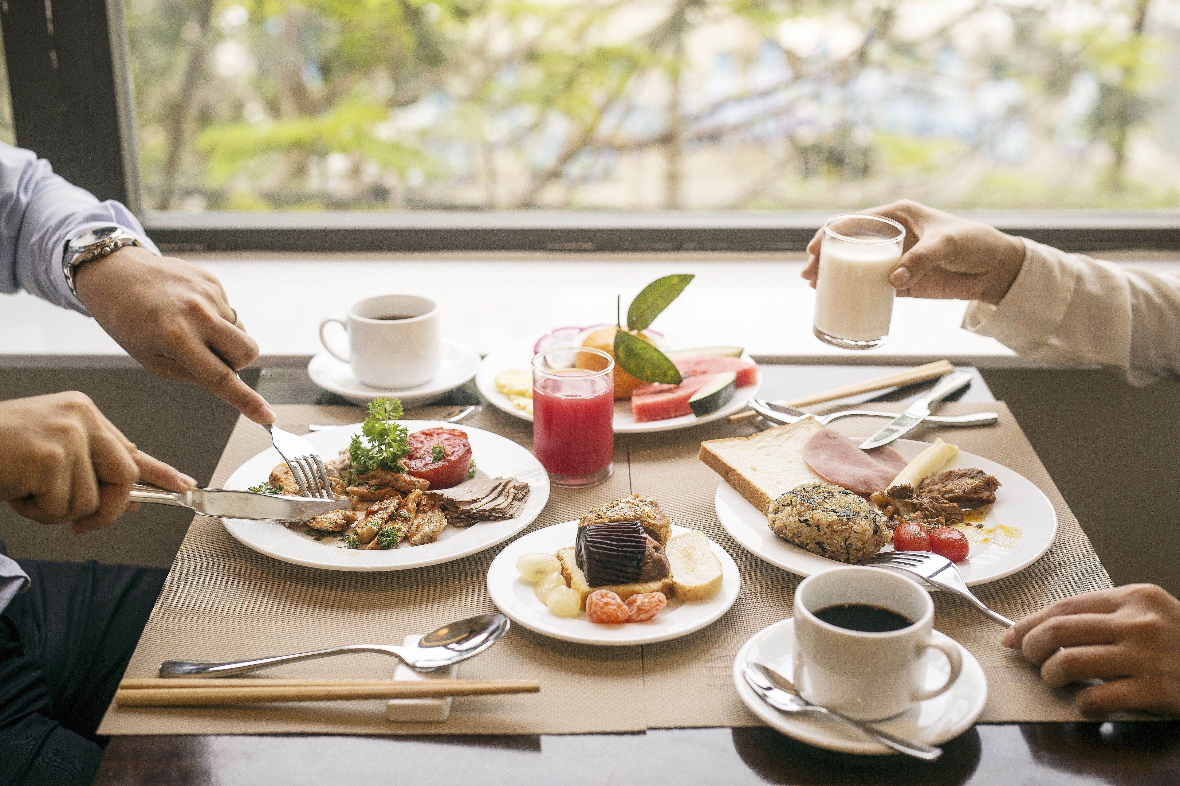 A breakfast setting with various dishes, utensils, and beverages on a table.