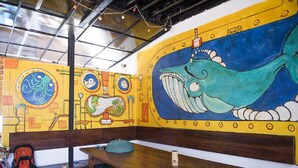 A room with a mural of a whale and a submarine, wooden benches, and a table. - Hangover Hostels at Mirissa (Mirissa)