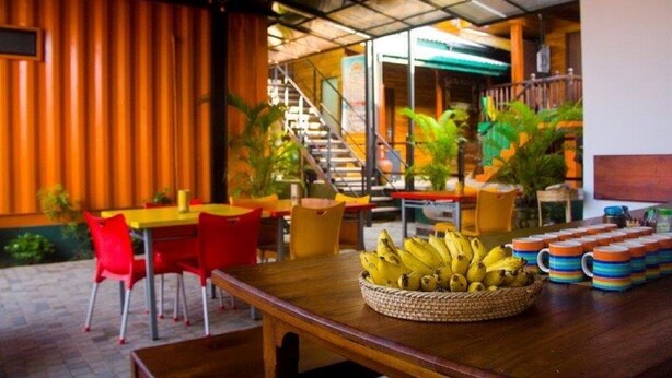A restaurant with a wooden interior, red chairs, and a table with a basket of bananas. - Hangover Hostels at Mirissa (Mirissa)