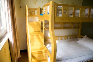Ein Etagenbett mit Holzbettrahmen, eine Schubladen unter dem unteren Bett und eine Matratze auf dem oberen Bett.