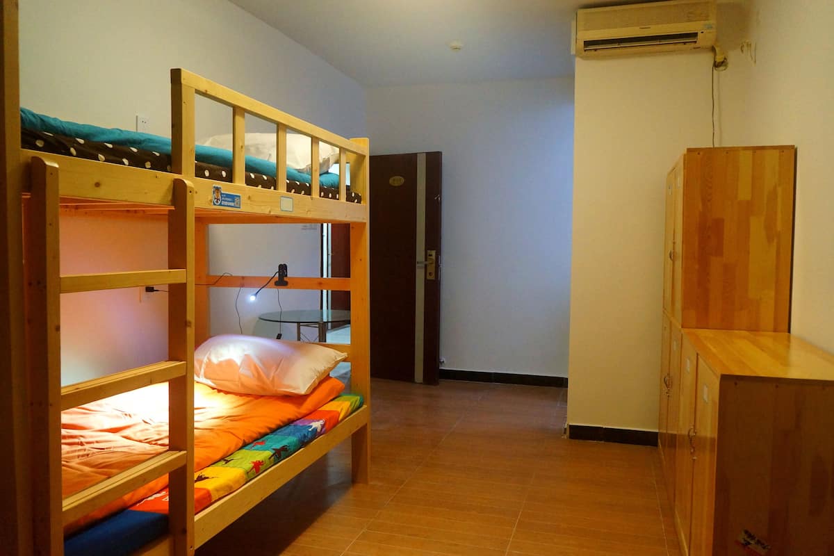 A bunk bed room with a desk and a wardrobe.