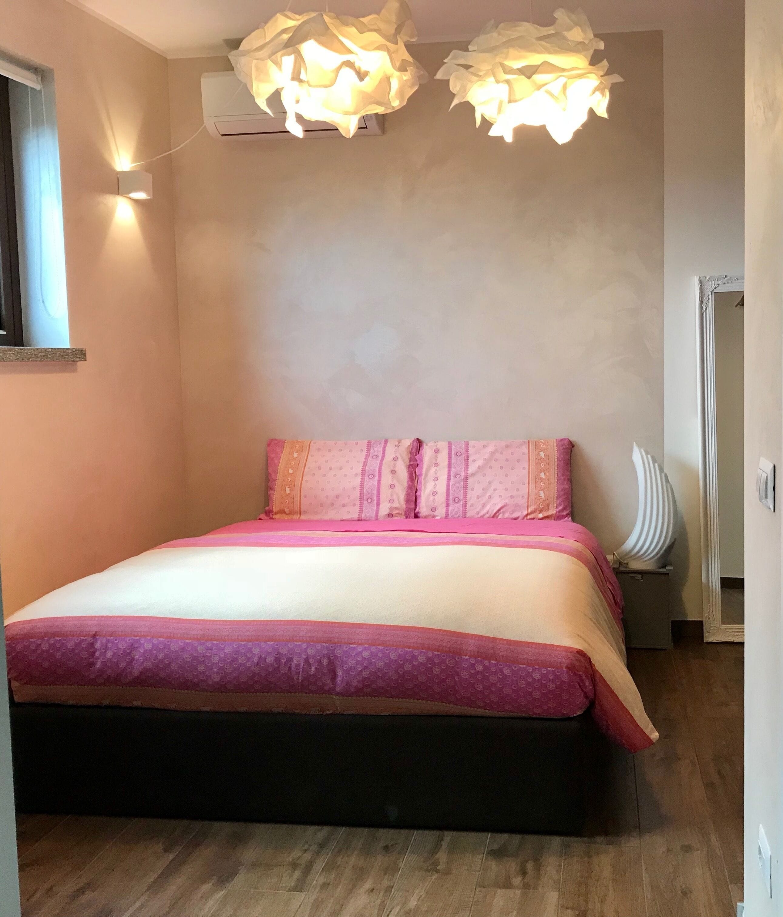 Une chambre avec un lit, un climatiseur fixé au mur et une fenêtre.