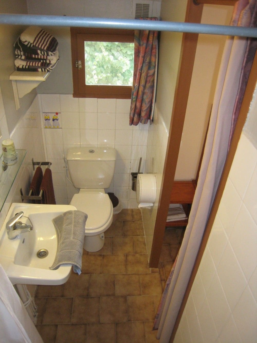 A small bathroom with a toilet, sink, and a window above the toilet.