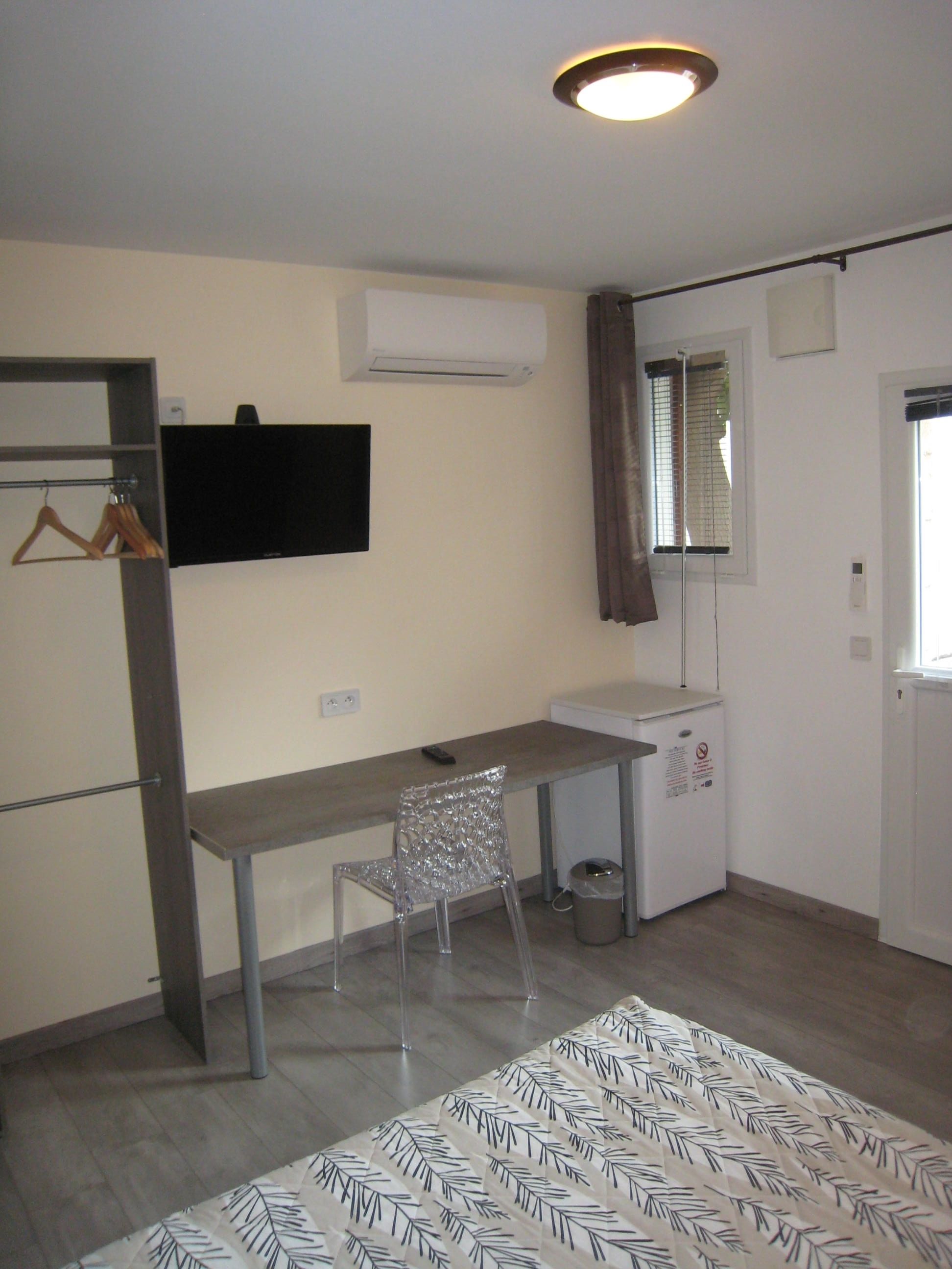 A small, modern room with a desk, chair, and a radiator.