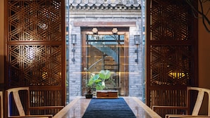 A traditional wooden interior with a central table and chairs, a spiral staircase, and a decorative wooden screen. - Beijing Le Zai Nan Luo Gu Xiang Wang Fu Jing Forbidden City Courtyard Hotel (Beijing)