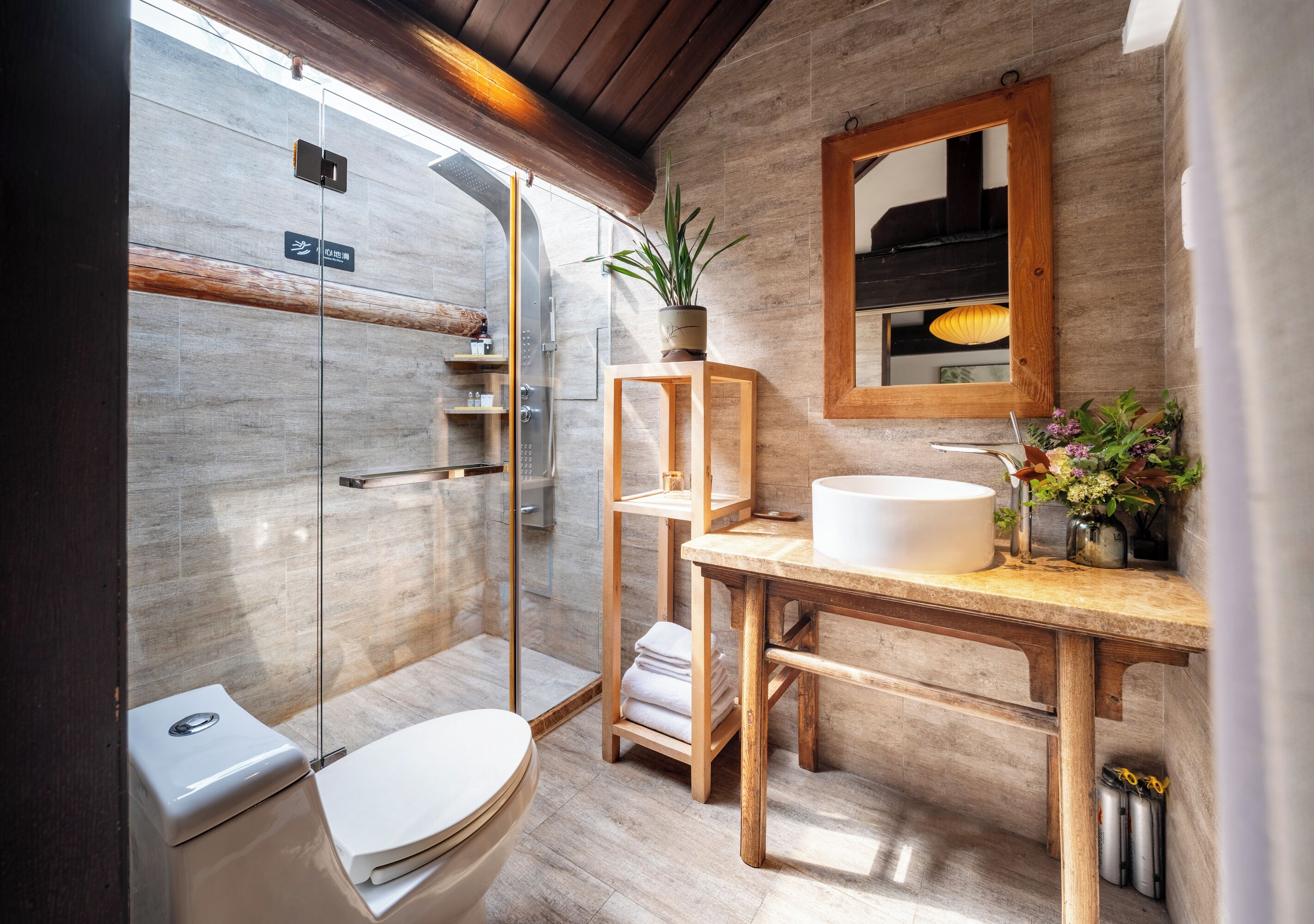 A modern bathroom with a glass shower enclosure, a wooden vanity, and a mirror above the sink.