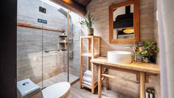 A modern bathroom with a glass shower enclosure, a wooden vanity, and a mirror above the sink.