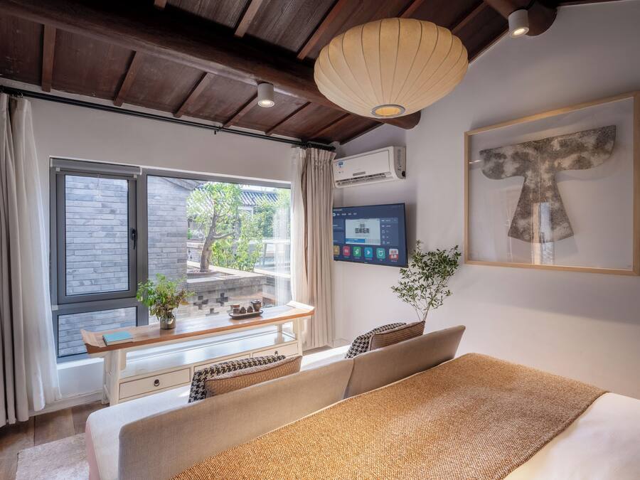 Una habitación de hotel moderna con una cama grande, un escritorio con computadora, una ventana con cortinas e iluminación en el techo.