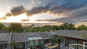 A traditional courtyard with modern glass structures, stone walls, and tiled roofs. - Beijing Le Zai Nan Luo Gu Xiang Wang Fu Jing Forbidden City Courtyard Hotel (Beijing)