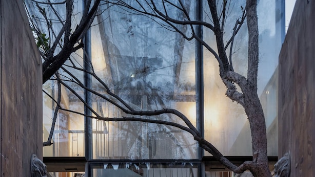 A modern interior with a spiral staircase, a wooden bench, and a large potted plant. - Beijing Le Zai Nan Luo Gu Xiang Wang Fu Jing Forbidden City Courtyard Hotel (Beijing)