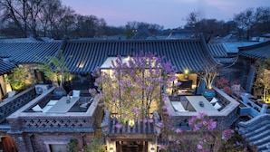 A traditional Korean-style building with a tiled roof, a central courtyard with a tree, and a small seating area with cushions. - Beijing Le Zai Nan Luo Gu Xiang Wang Fu Jing Forbidden City Courtyard Hotel (Beijing)