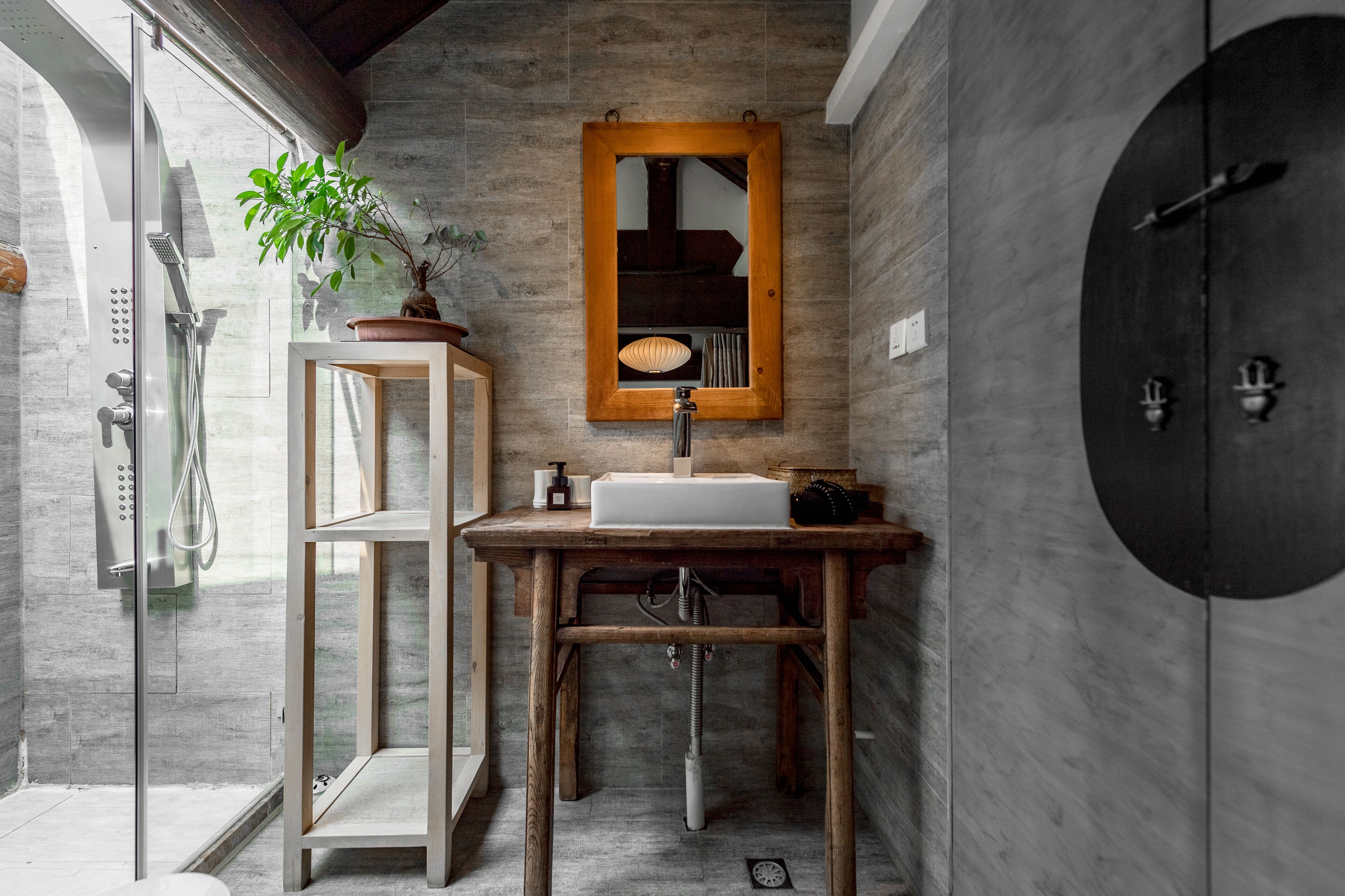 A bathroom with a wooden vanity, a mirror, a sink, and a shower.