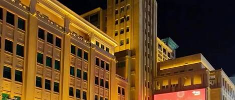 A large building with a clock tower, multiple floors, and illuminated signage.