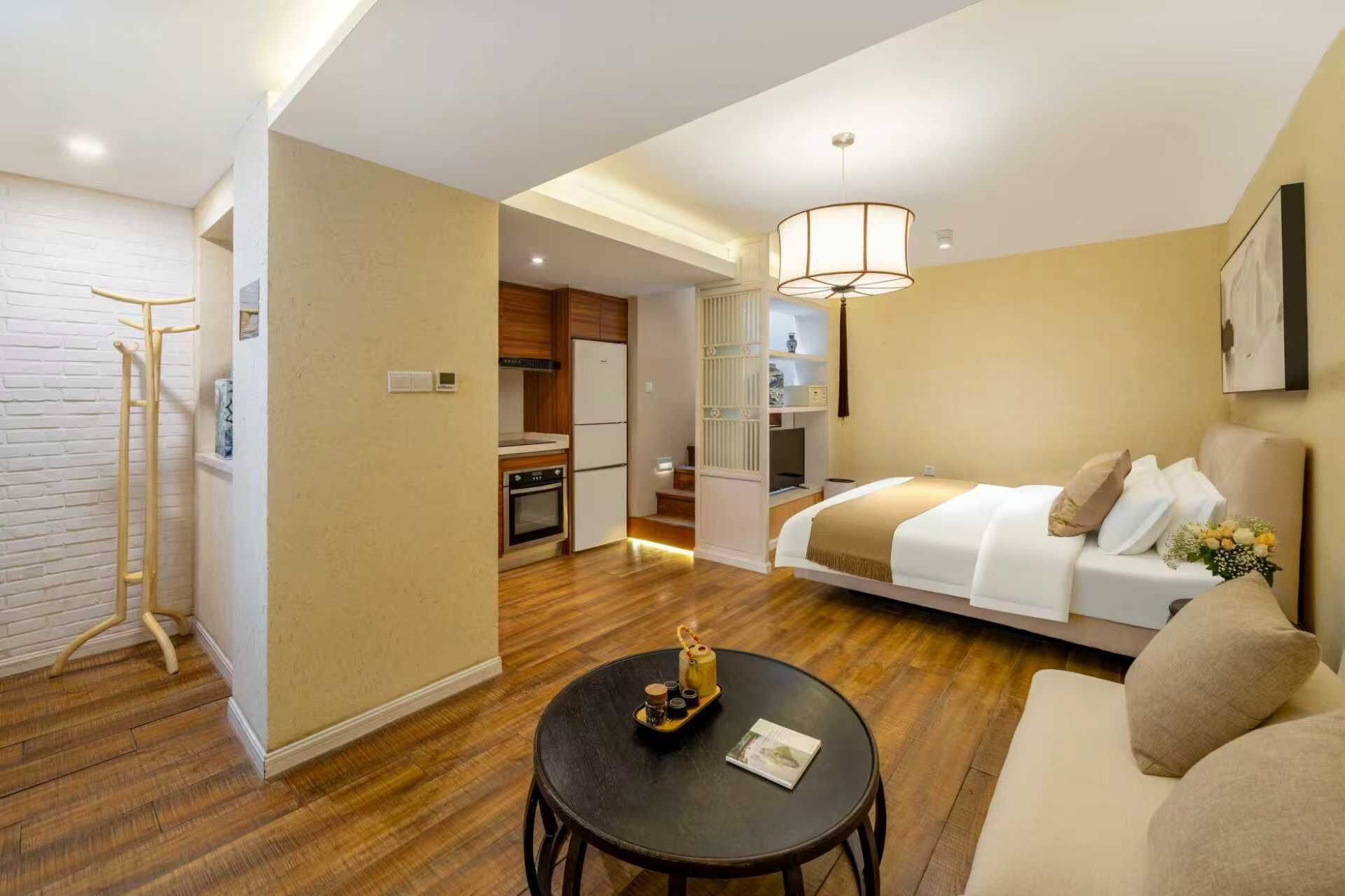 Une chambre d’hôtel comprenant un lit, une petite table avec un plateau, un porte-manteau, une kitchenette et une salle de bain.