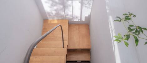 A wooden staircase with a metal handrail, leading to a landing with a framed architectural drawing.