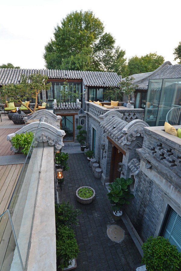 A traditional courtyard with stone architecture, potted plants, and outdoor seating. - Beijing Le Zai Nan Luo Gu Xiang Wang Fu Jing Forbidden City Courtyard Hotel (Beijing)