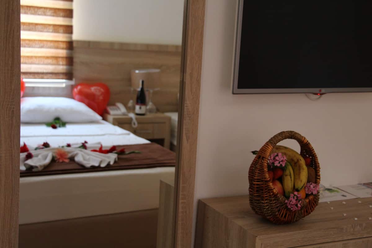 Una camera da letto con un letto, un comodino con una bottiglia e un cesto di vimini pieno di frutta.