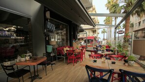 An outdoor café with wooden tables and chairs, a glass enclosure, and a view of the street. - The Marmaris Boutique Hotel (Marmaris)