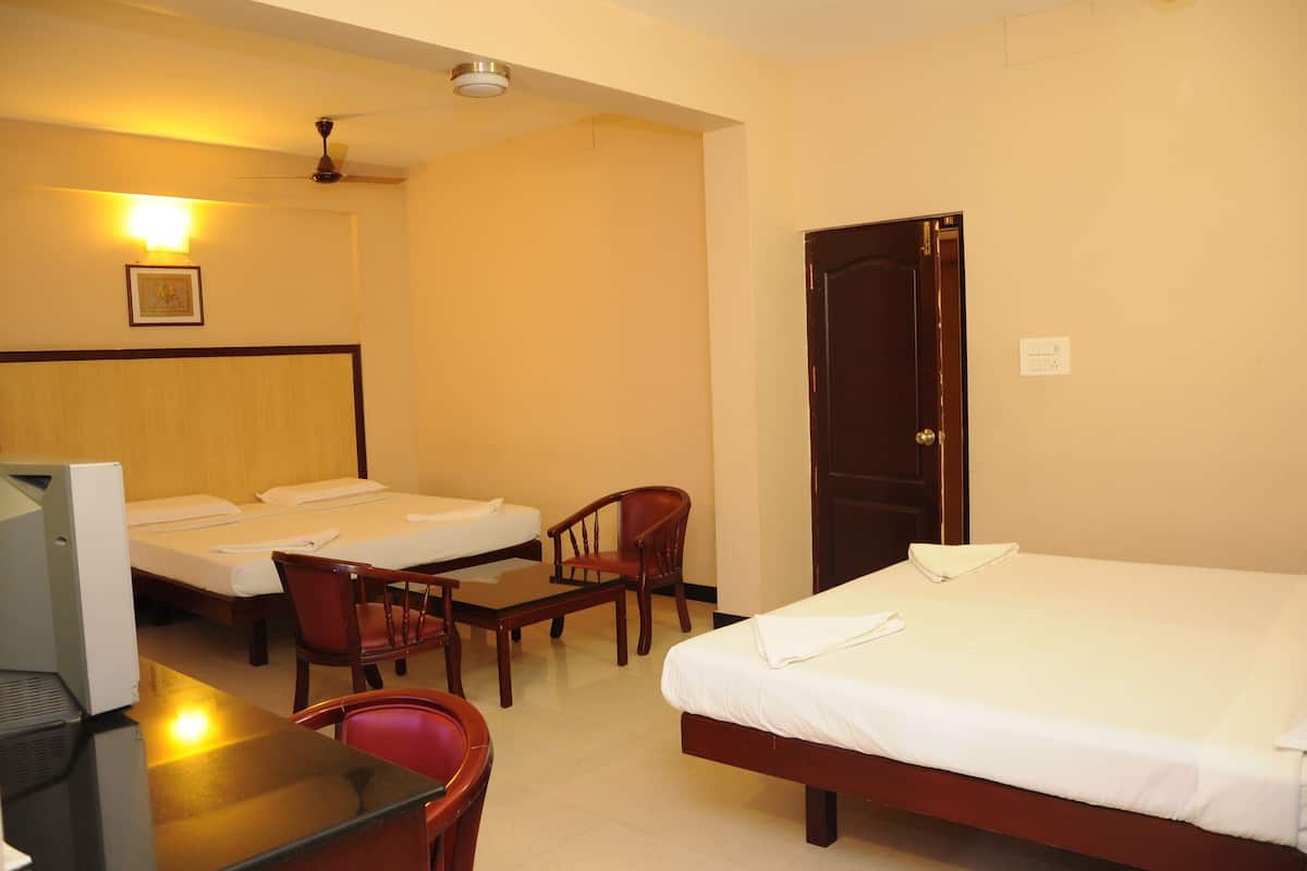 A hotel room with two single beds, a desk with a computer, a chair, and a wooden door.