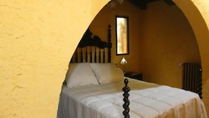 A bed in a room with a yellow wall and an arched doorway. - Casería La Infiesta (Caso)