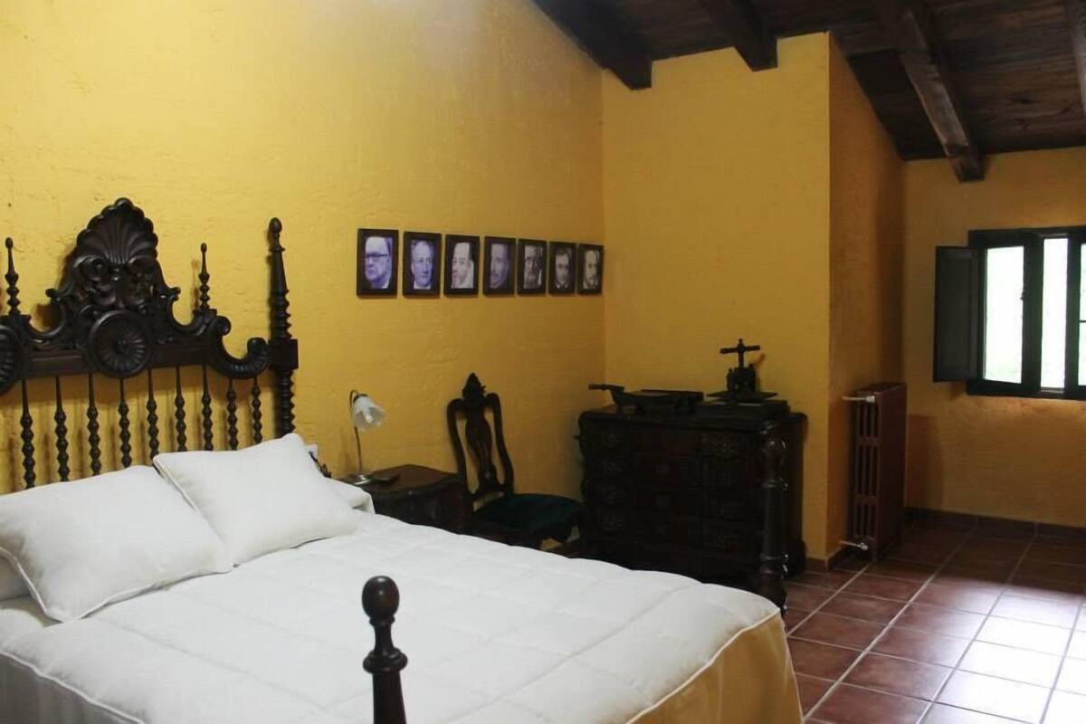 Une chambre à coucher avec un lit, une commode, une chaise et une fenêtre.