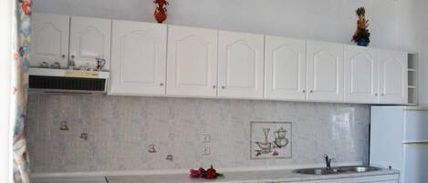 A kitchen with white cabinets, a washing machine, a stove, and a sink.