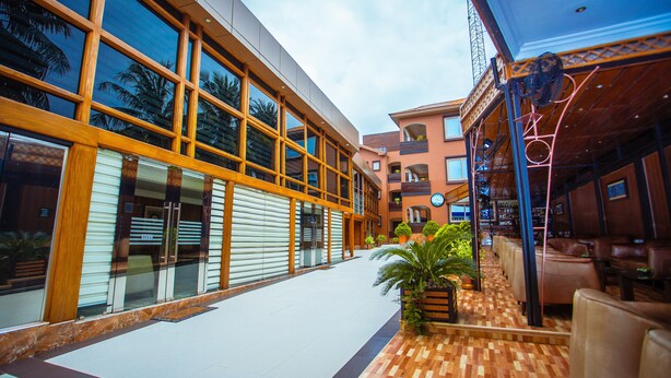 Un interior de hotel moderno con un pasillo central, suelo de madera y una zona de estar con mesas y sillas.