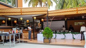 Un área de bar al aire libre con una terraza de madera, una barra y un escenario con fondo.