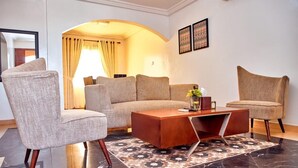 Una sala de estar moderna con un sofá, dos sillones, una mesa de centro y un tapete estampado.